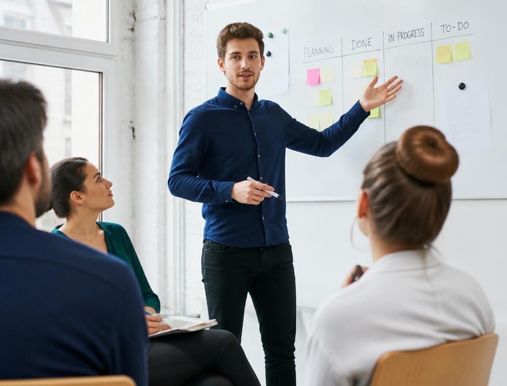 A man presenting to colleagues beside a whiteboard